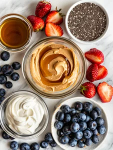 Ingredients for high protein yogurt snack including Greek yogurt, peanut butter, berries, and chia seeds